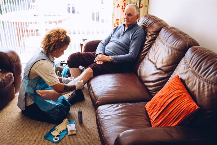 A carer helping an elderly patient put on bandages