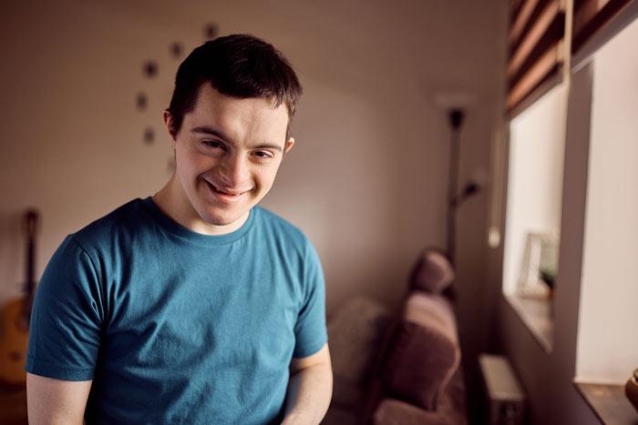 A young person with downs syndrome smiling at the camera