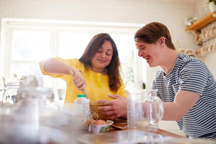 A carer helping a patient with downs syndrome with baking